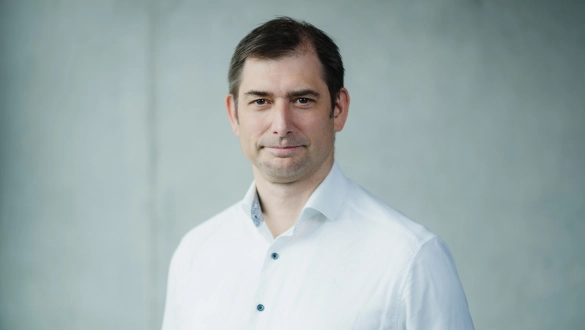 Professioneller Mann in weißem Hemd vor grauem Hintergrund.