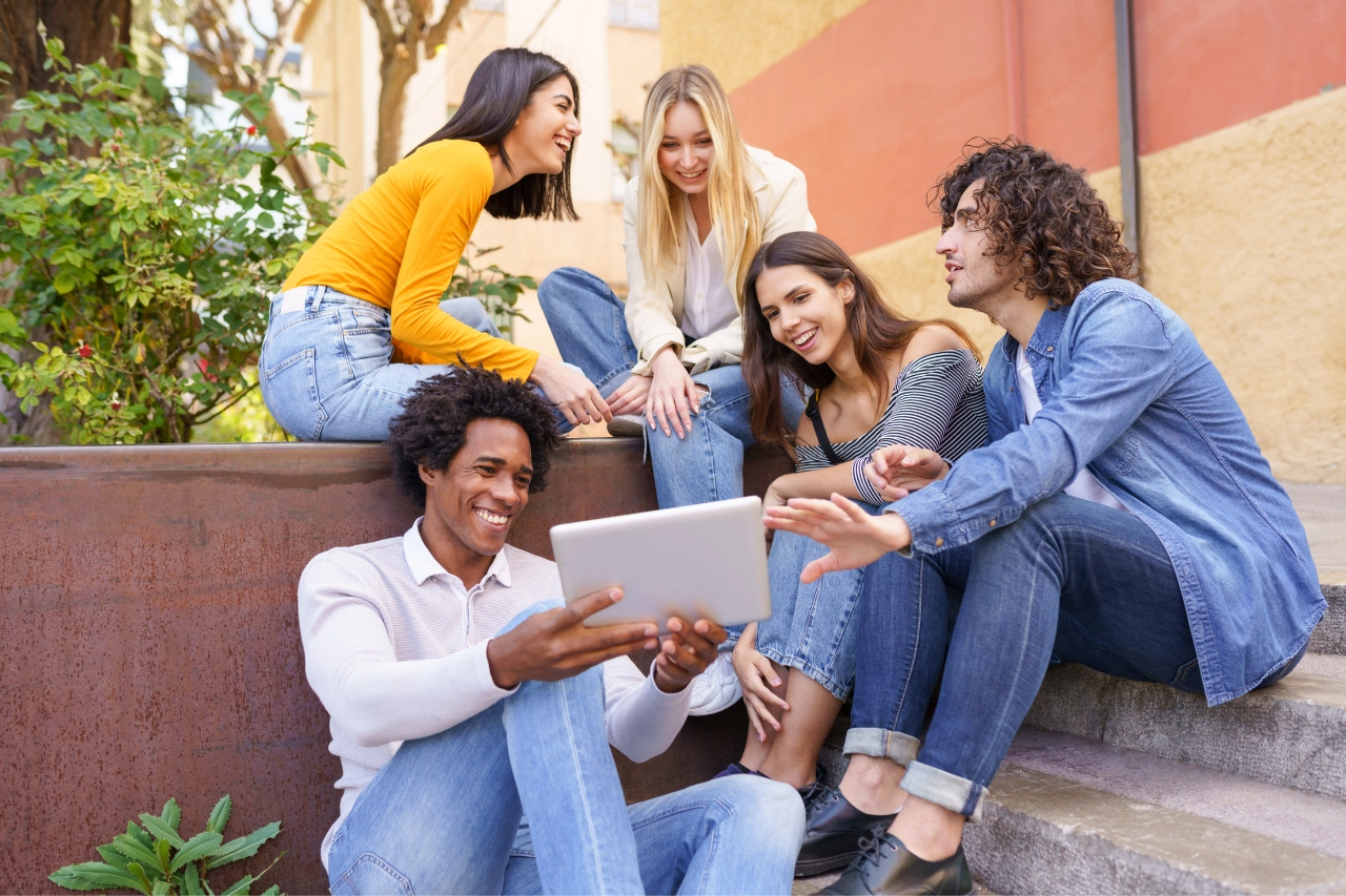 Junge Erwachsene genießen Outdoor-Meeting mit Tablet, fröhliche Teamarbeit.