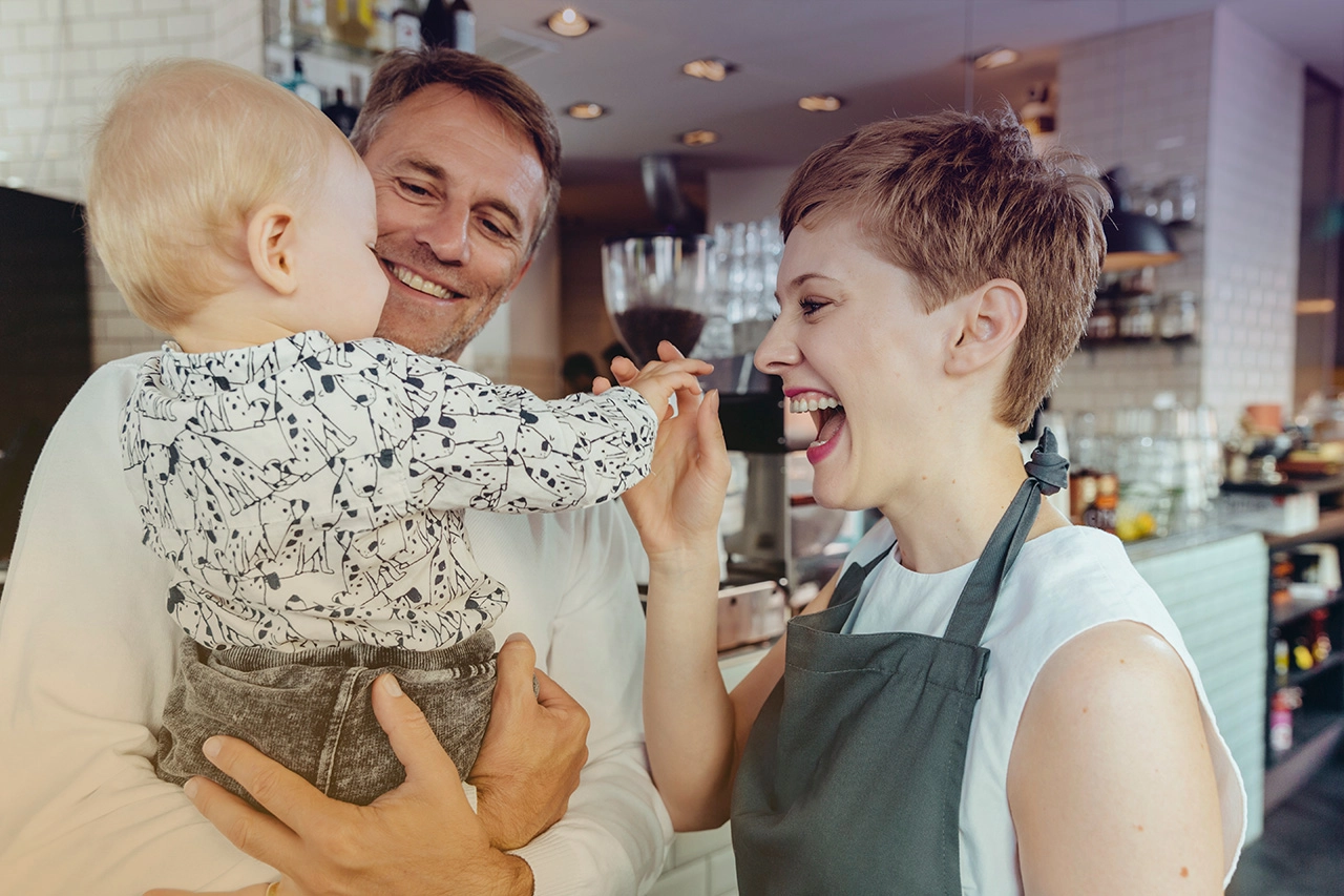 Familienfreundliches CafÃ©-Erlebnis: Lächelnde Eltern mit Baby genießen den Moment.